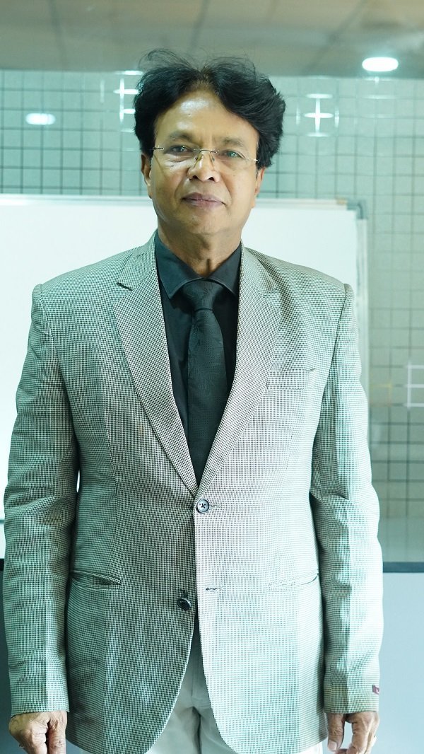 Dr. K. L. Prajapati standing confidently in a light blazer and black formal attire.