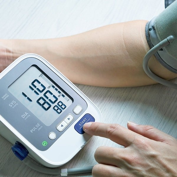 Person measuring blood pressure using a digital blood pressure monitor on their arm.